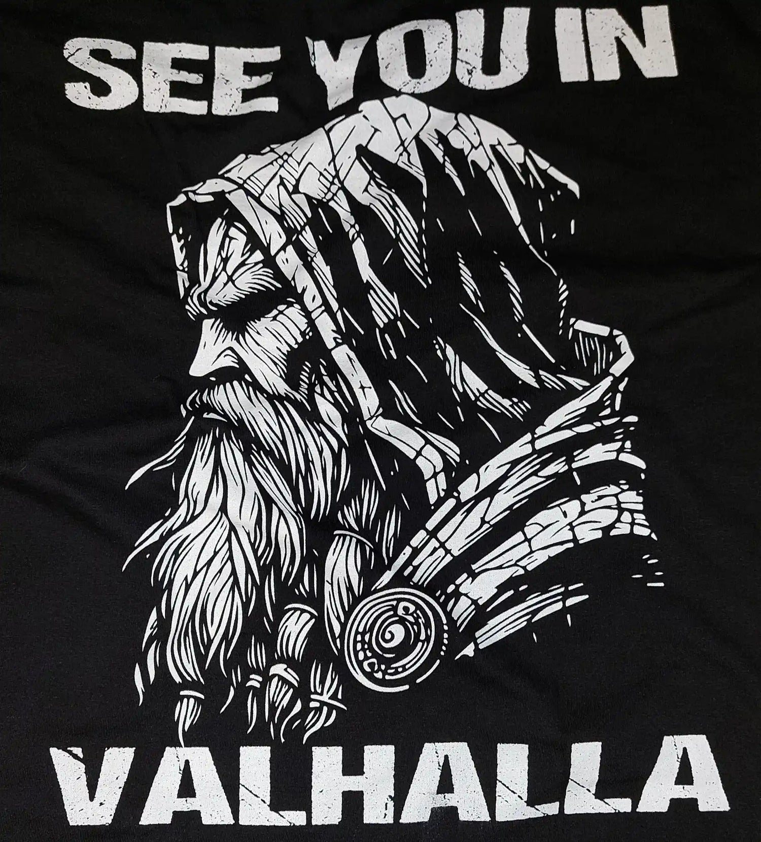 Seitenansicht eines bärtigen nordischen Kriegers mit dem Text ‘WIR SEHEN UNS IN VALHALLA’ darüber und darunter.